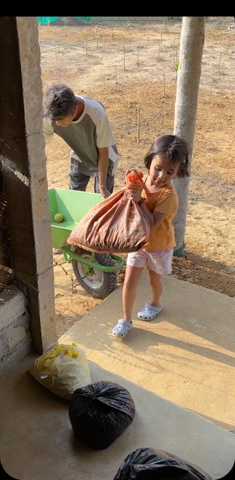 A child helping carry a sack at the farm
